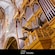 A pipe organ decorated with wood carvings that are shaped like cherubs, flowers, leaves and lattices